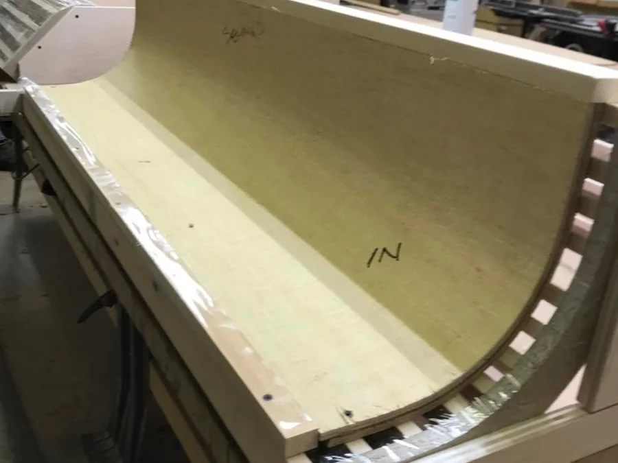 Curved bar cabinet as a raw plywood form being shaped on the shop bench