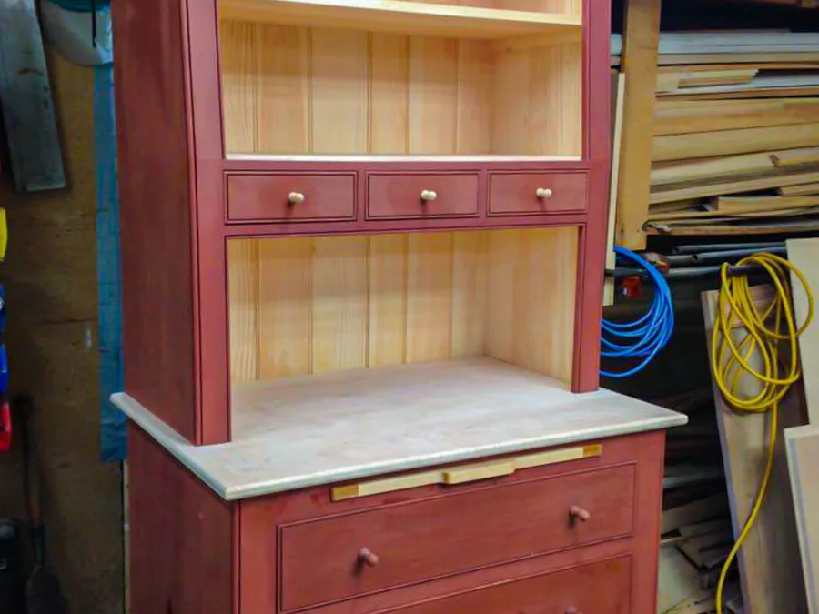 Slant-front breakfront hutch in red milk paint with open pine shelving and drawers