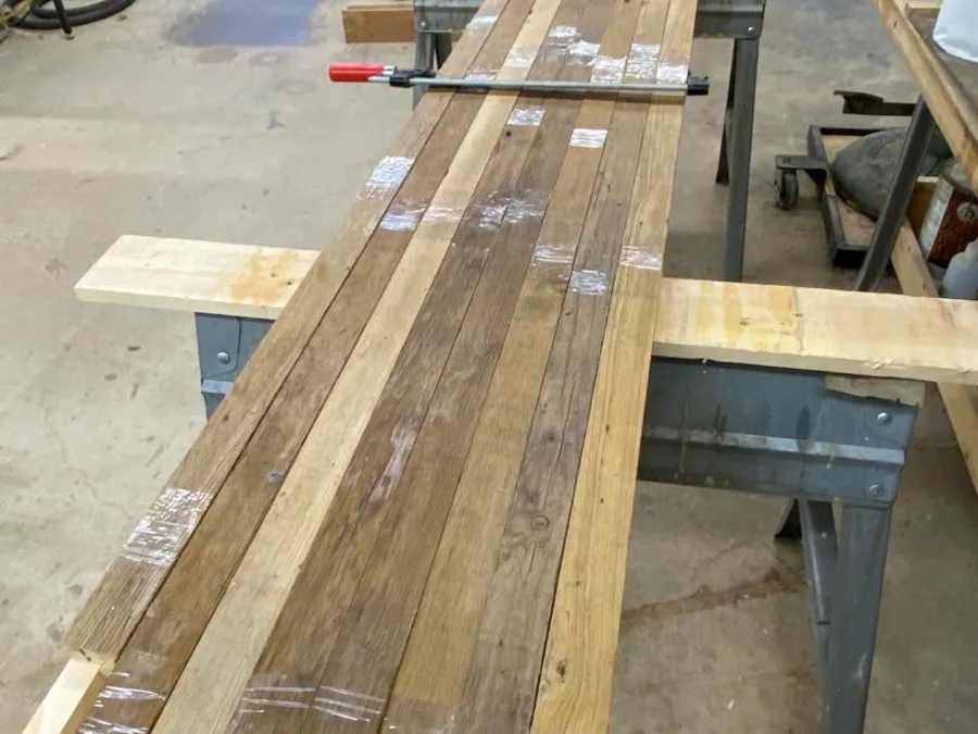 Reclaimed weathered boards clamped on sawhorses in the shop, labeled for a build