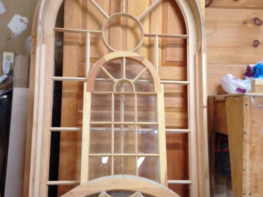Raw arched window muntin work in unfinished wood resting in the shop