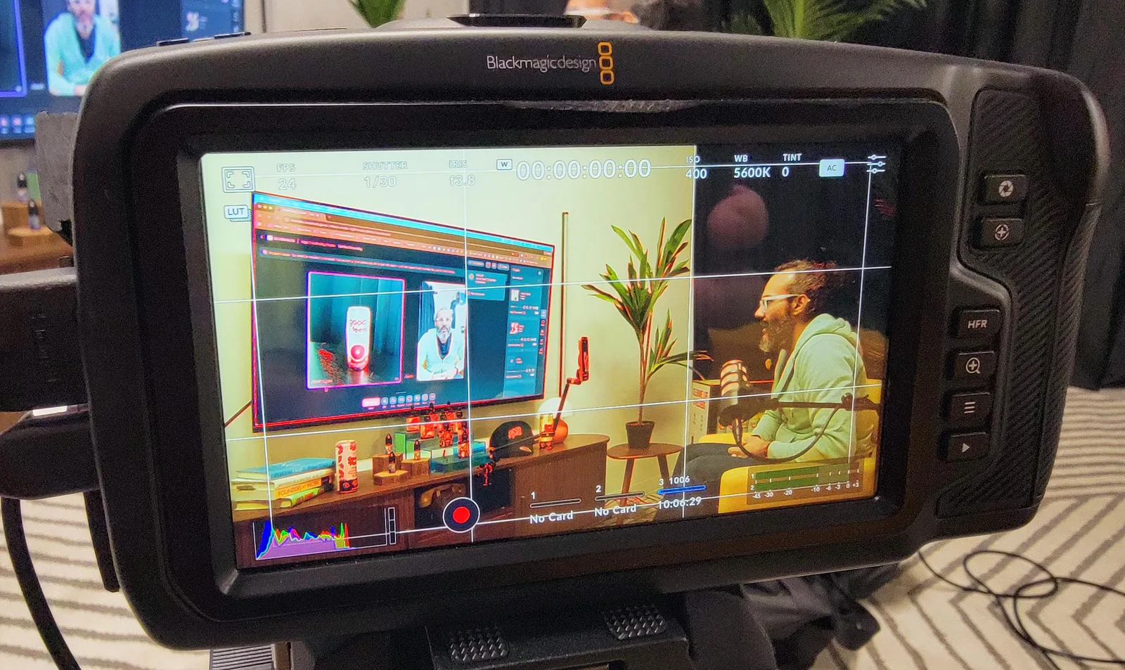On set for a High Functioning recording — a Blackmagic camera monitor framing host Jason Reposa at the mic, with the Good Feels product set in the foreground
